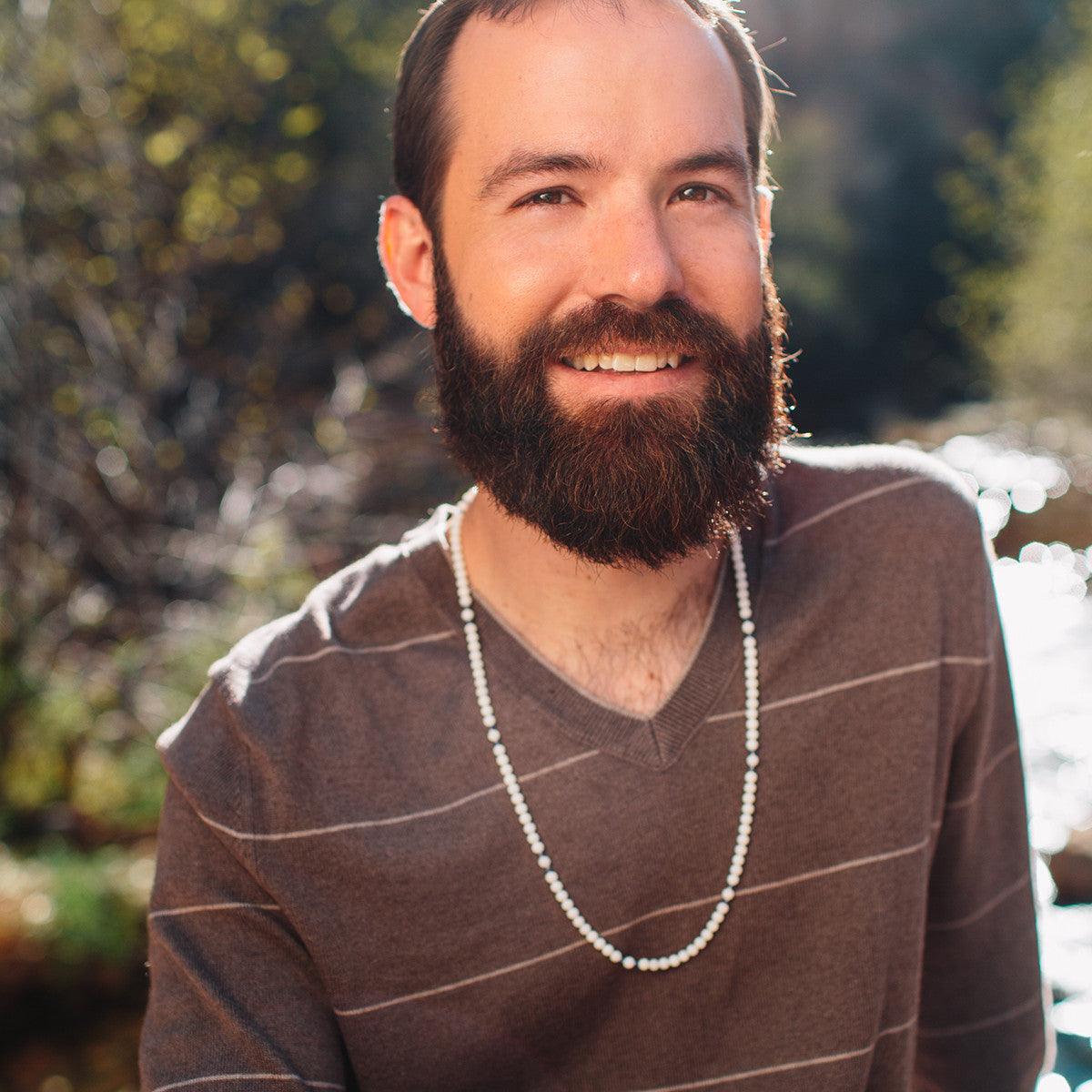 A man wearing a crystal healing Angelfire necklace known for its ability to help you have more positive and constructive thoughts