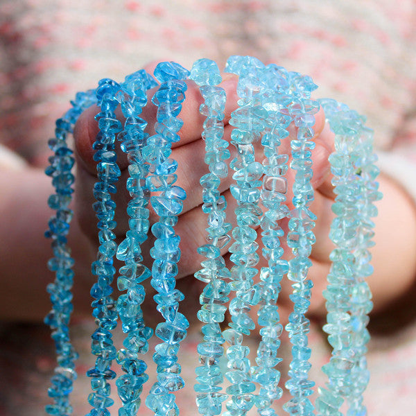 Hands holding many crystal healing Aquamarine necklaces known for heightening your awareness of truth
