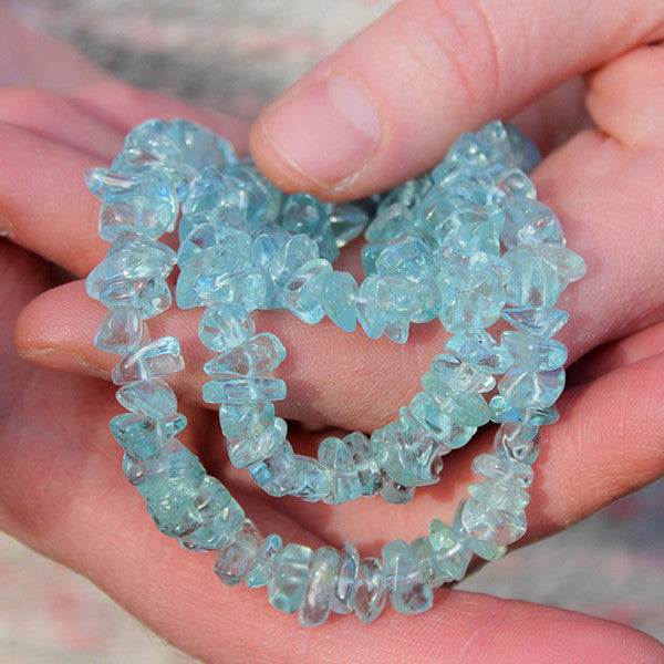 Hands holding a crystal healing Aquamarine necklace known for heightening your awareness of truth