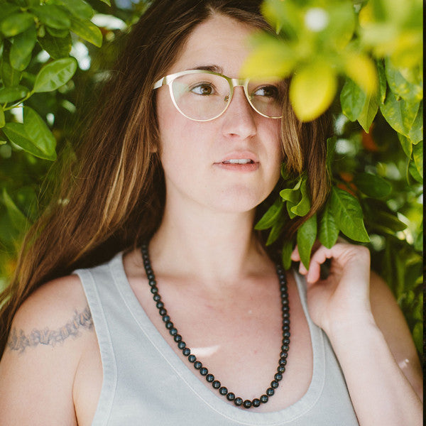 A woman in nature wearing a Bloodstone healing gemstone necklace, known for boosting the immune system through crystal healing