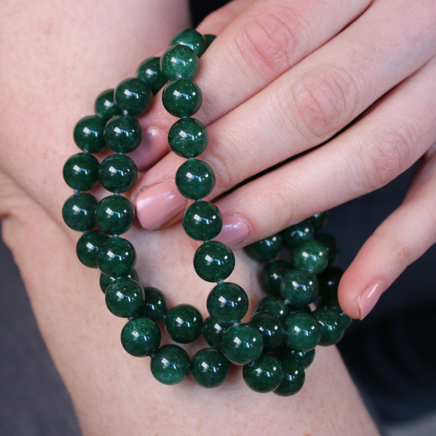 Crystal healing Dark Green Aventurine necklace known for strengthening and purifying organs being played on an arm