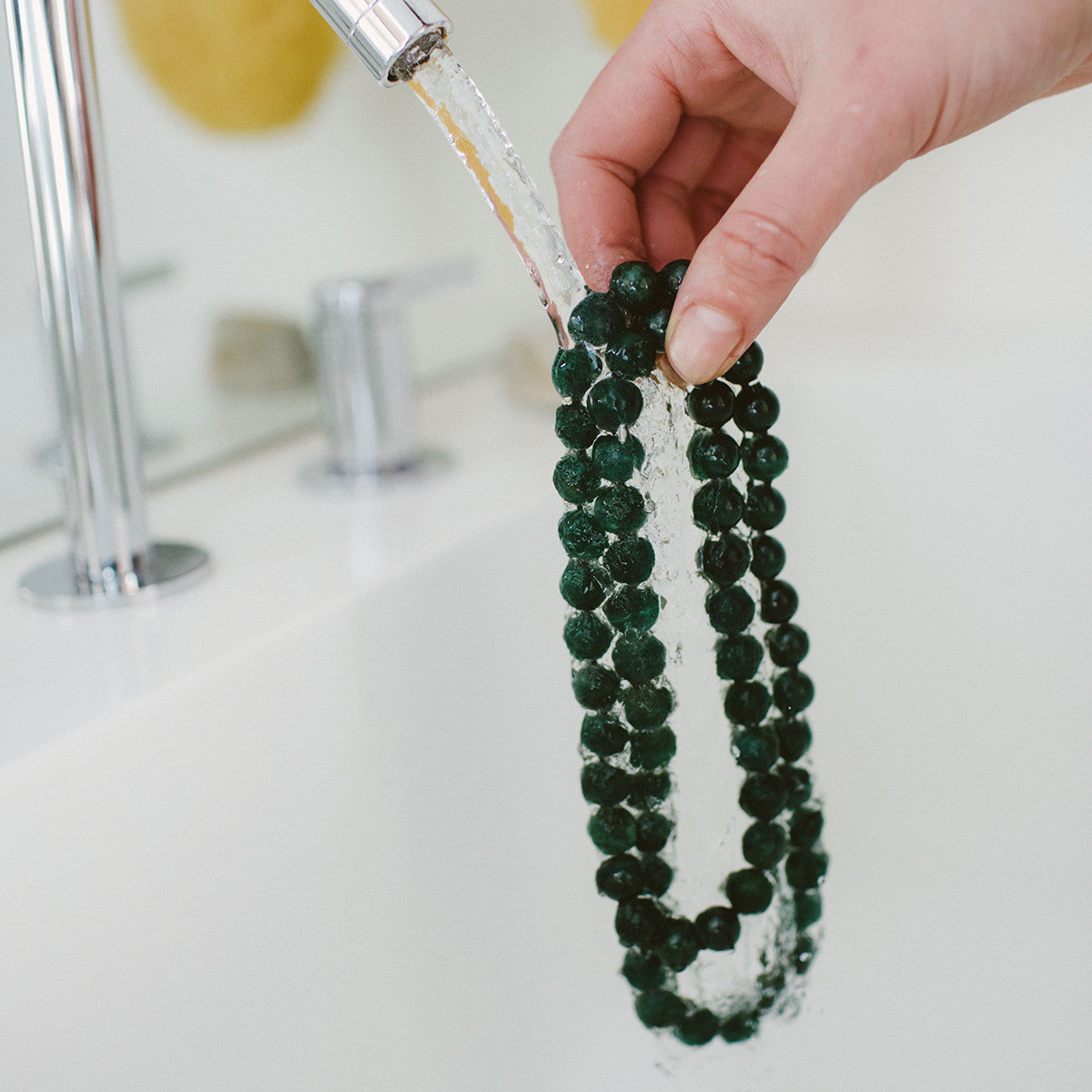 Crystal healing Dark Green Aventurine necklace known for strengthening and purifying organs is being cleansed with water