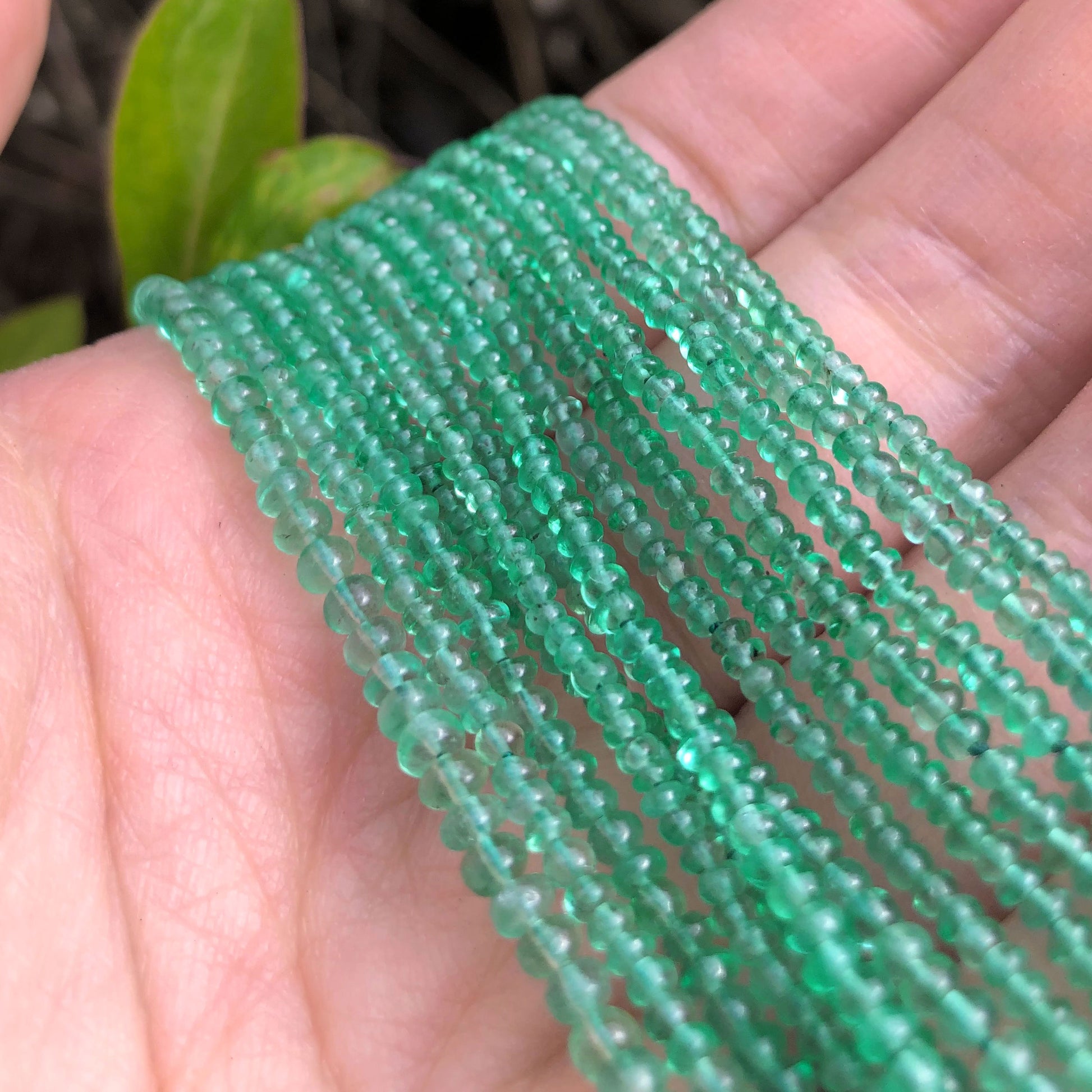 A hand full of many crystal healing Emerald necklaces known for healing The Physical Body