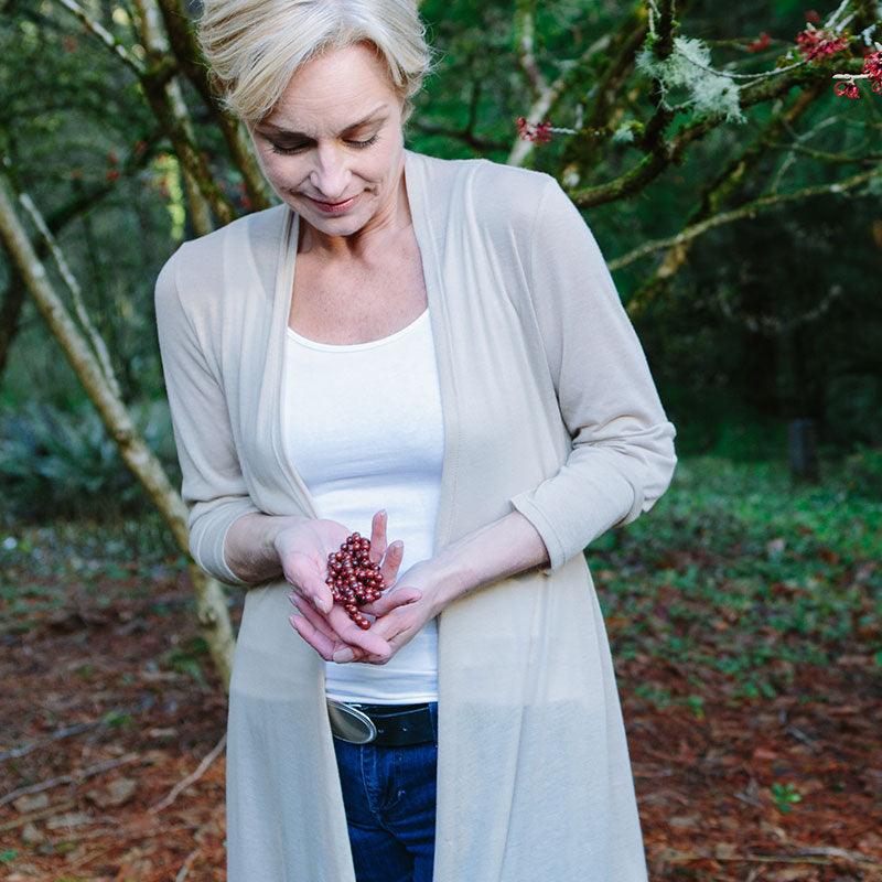 A woman hold a crystal healing Poppy Jasper necklace known for helping boost energy