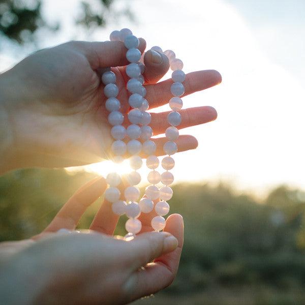 Light shines through a crystal healing Blue Lace Agate necklace known for increasing confidence and self-worth