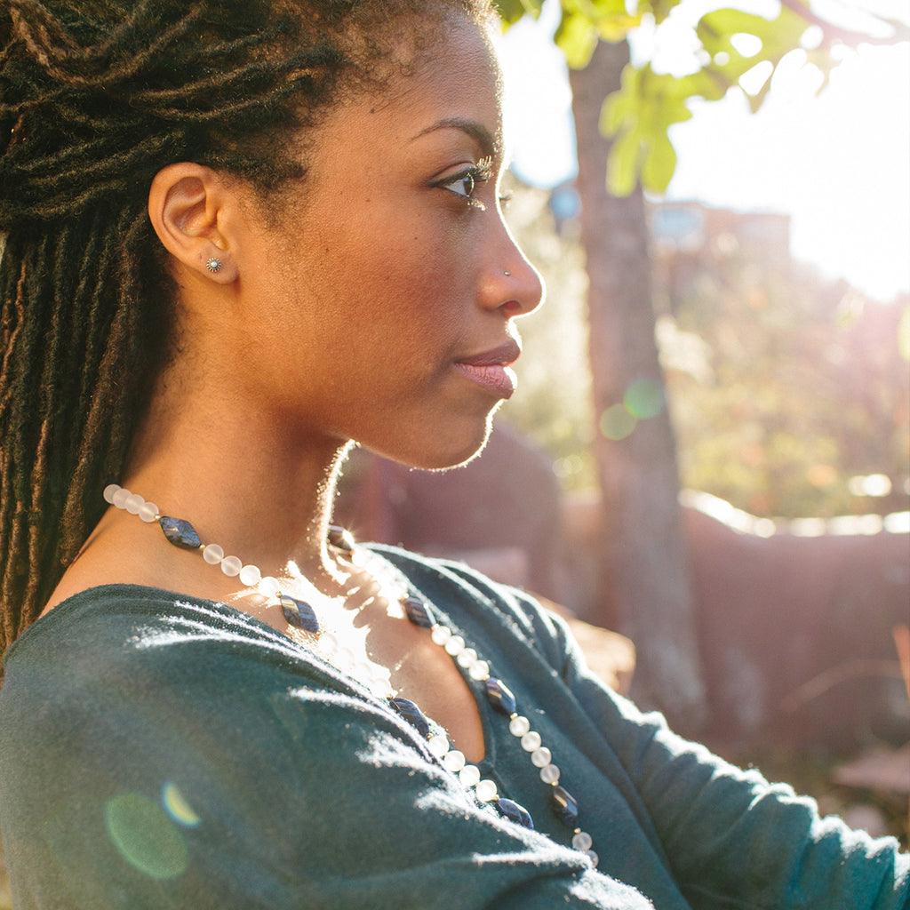 A woman wearing a crystal healing Blue Phoenix necklace known for letting go of limiting habits and attitudes