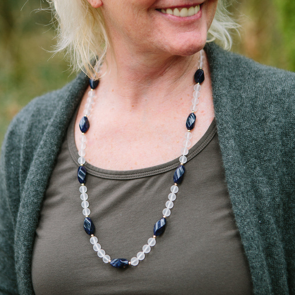 A woman wearing a crystal healing Blue Phoenix necklace known for letting go of limiting habits and attitudes
