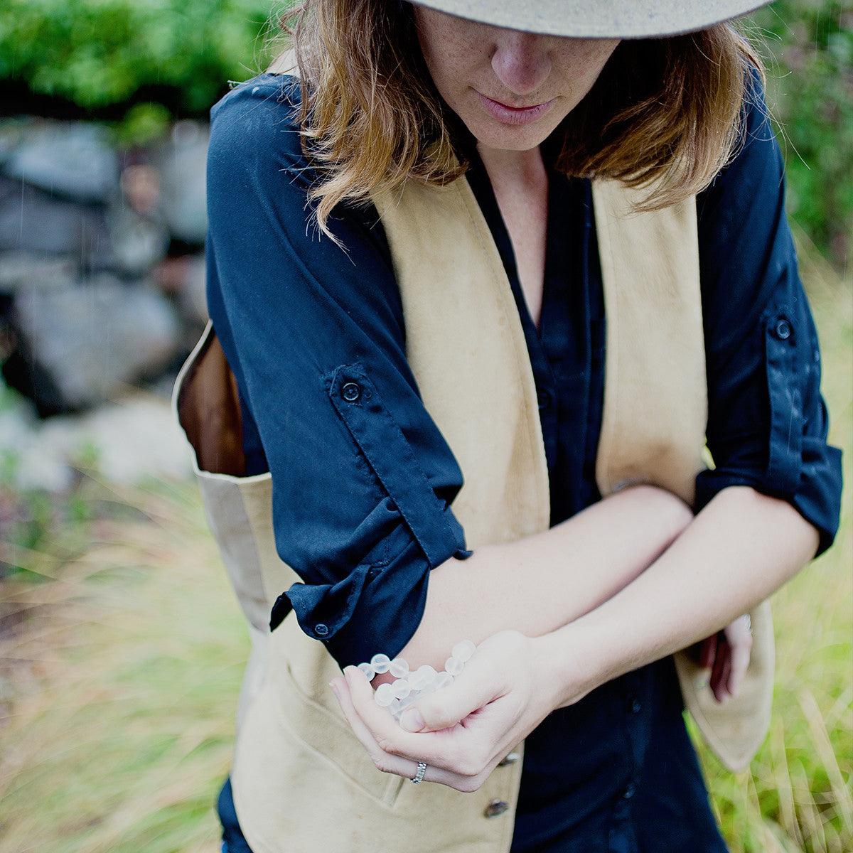 A woman holding a Crystal healing Quartz gemstone necklace known for attracting life-force