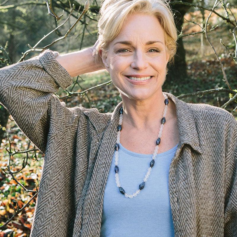A woman wearing a crystal healing Blue Phoenix necklace known for letting go of limiting habits and attitudes