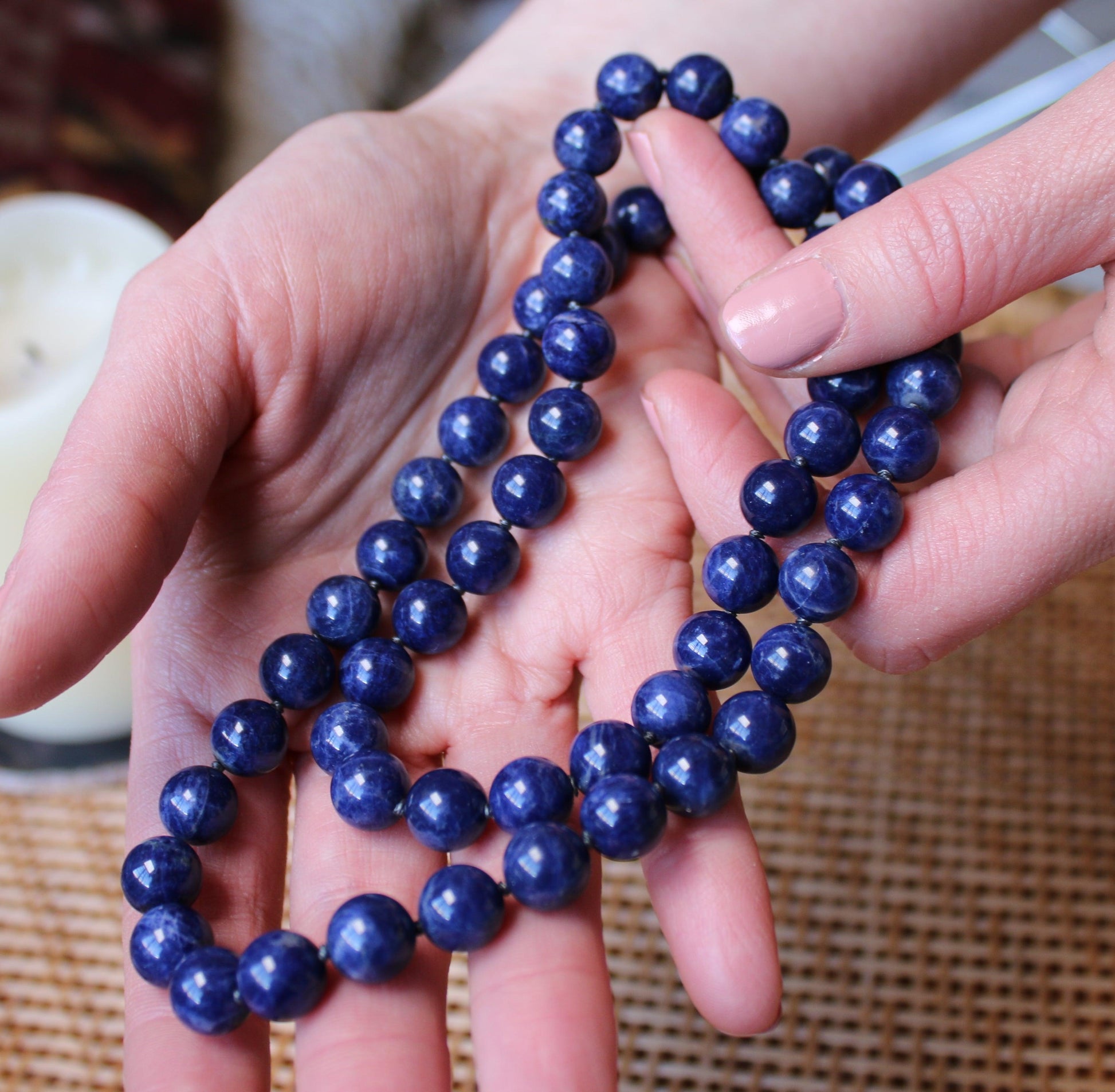 Two hands holding a Crystal healing Sodalight necklace for energy protection and purifying the aura 