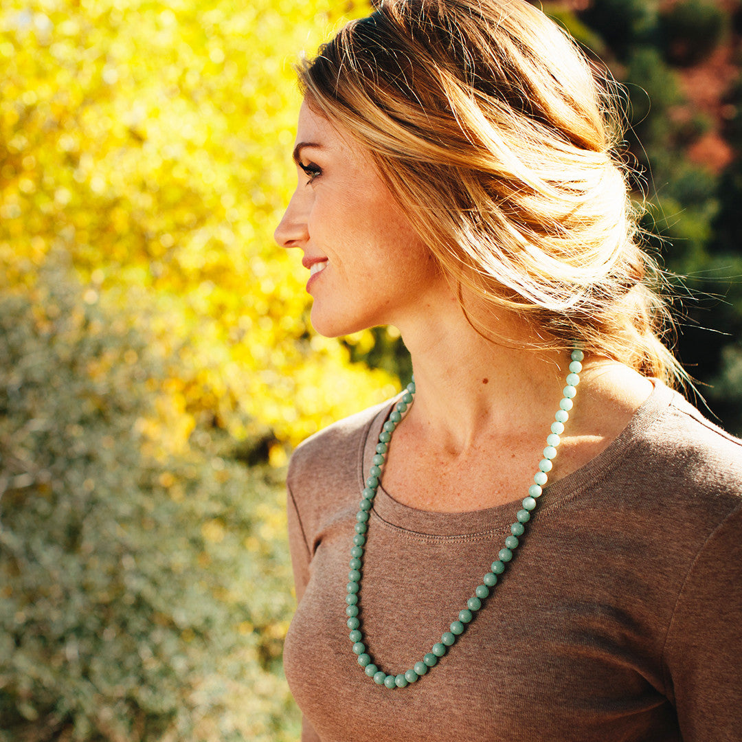 A woman wearing a crystal healing Light Green Aventurine gemstone necklace known for uplifting your physical health