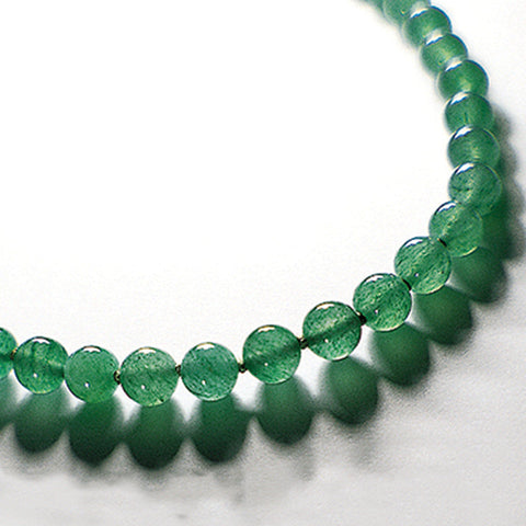 Light green aventurine therapeutic gemstone necklace displayed on a white table.