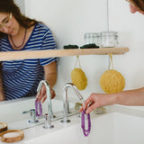 Amethyst necklace being washed and cleansed in a bathroom with woman in the room.