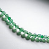 Light green emerine therapeutic gemstone necklace displayed on a white table.