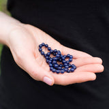 Purple indigo gemstone necklace held in a young woman's hands.