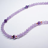 Purple Light Stream therapeutic gemstone necklace being displayed on a white table.