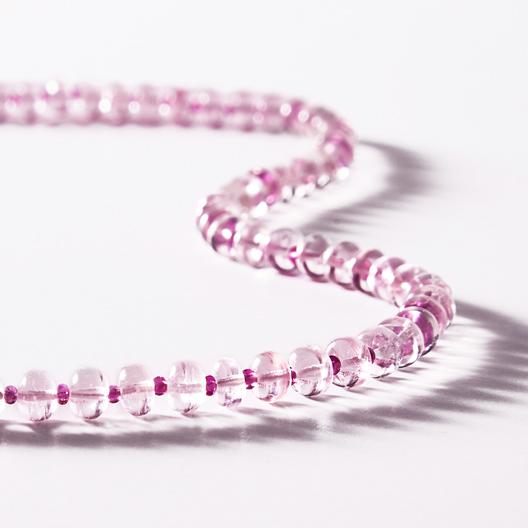 Pink Radiance therapeutic gemstone necklace displayed on a white table.