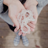 Quartz therapeutic gemstone necklace being held in a young woman's hand.