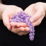 Lavender therapeutic gemstone necklace being held in a woman's hand.