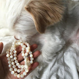 White Mother of Pearl therapeutic gemstone necklace being held by a woman.