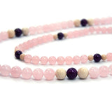 Pink and black Rose Flame therapeutic gemstone necklace displayed on a white table.