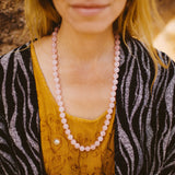Pink Roselle therapeutic gemstone necklace being worn around the neck of a young woman.