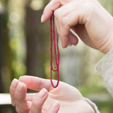 Ruby therapeutic gemstone necklace being held by a woman in her hands.